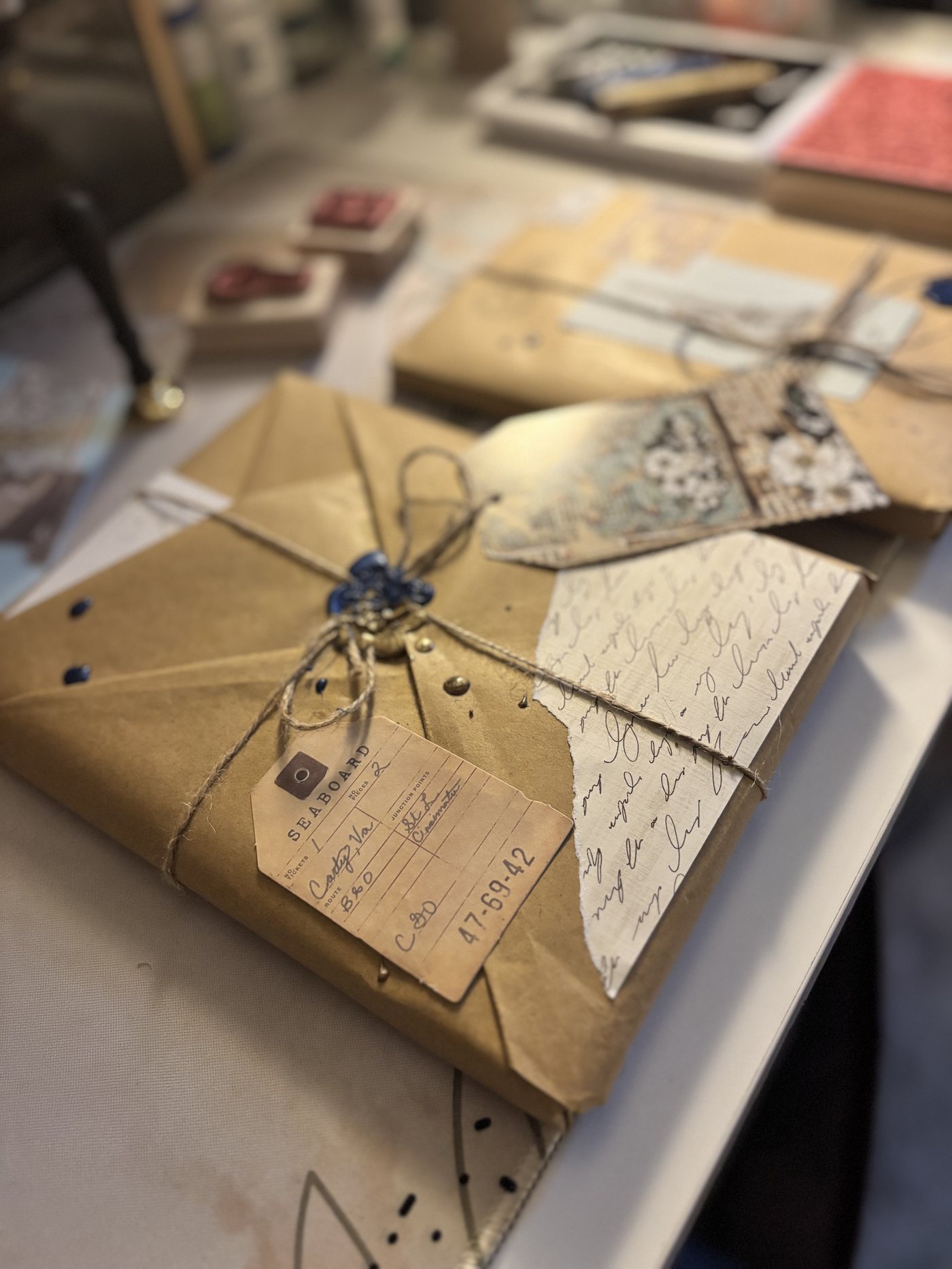 A kraft-wrapped Steeped & Sealed parcel with a vintage shipping tag, twine, and blue wax seal